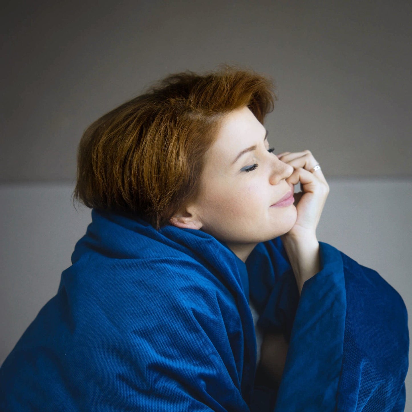 Frau mit roten Haaren unter blauer Gewichtsdecke aus Baumwolle