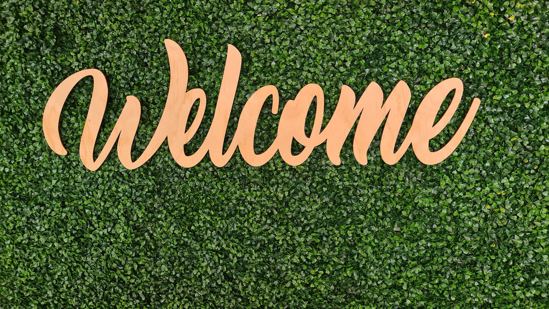 Einladender Schriftzug 'Welcome' in freundlicher Handschrift auf einem pastellfarbenen Hintergrund, umgeben von floralen Verzierungen.